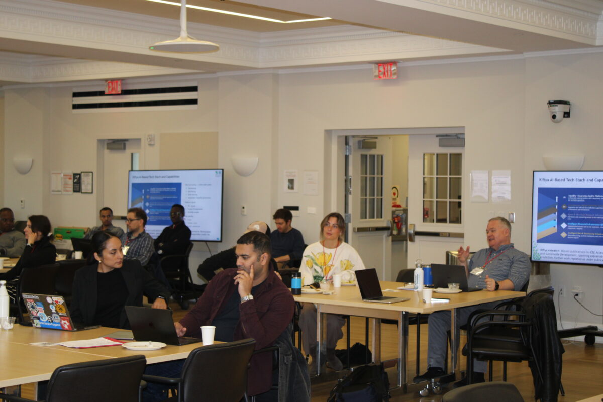 Attendees at working tables during a summit session, with presentation screens on both walls
